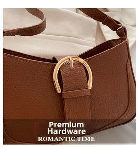 Close-up of vintage brown pebble leather handbag featuring a golden horse-bit buckle