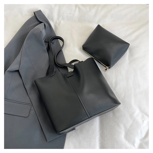 Detail view of black faux leather tote and matching zipper pouch on gray blazer jacket