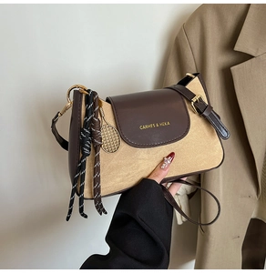 Dettaglio della borsa a tracolla in tela e pelle marrone con logo dorato e ciondolo racchetta