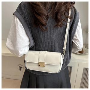 Detail of the elegant gold metal clasp on a cream leather minimalist square shoulder bag