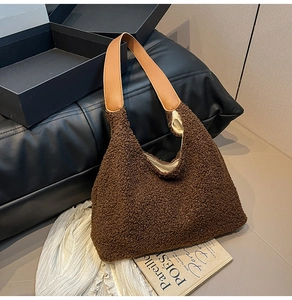 Detailed close-up of brown plush tote bag with camel leather strap on textured surface