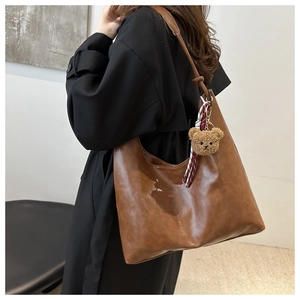 Detail einer braunen Vintage-Hobo-Tasche mit süßem Plüschbär-Anhänger-Dekor