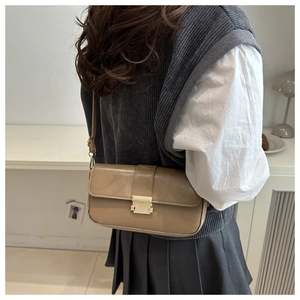 Close-up of a khaki crossbody bag with golden metal clasp shown on model shoulder