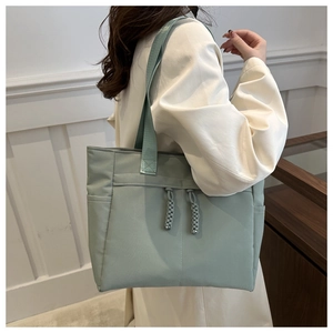 Dettaglio della borsa tote in tela verde menta con nodi decorativi e manici larghi