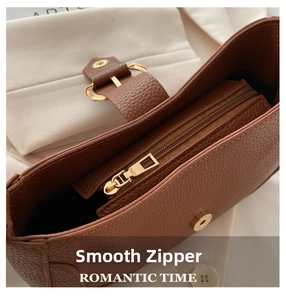 Detail of brown litchi grain leather bag showing the gold metal zipper and magnetic closure