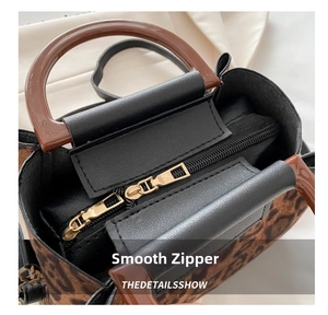 Detail of smooth gold double zippers and leopard print pattern on a stylish handbag