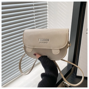 Detail of beige saddle bag showing the embossed logo text and soft faux leather texture