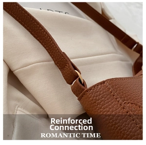 Close-up of reinforced strap connection and litchi grain texture on brown crossbody bag