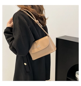 Détail d'un sac porté épaule marron clair avec boucle nœud argentée et bandoulière nouée