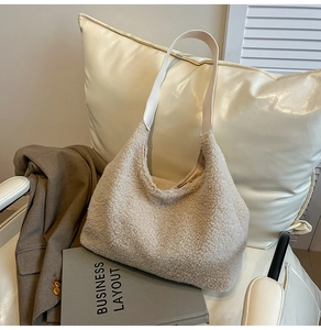 Close-up of beige faux fur hobo bag with white leather strap in a minimalist setting