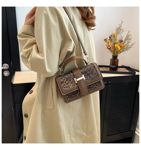 Close-up of leopard print crossbody bag with golden buckle on a beige trench coat