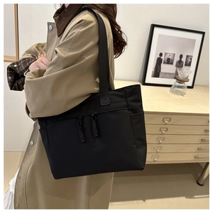Detail of black tote bag with double front zippers and woven pulls in a modern office setting