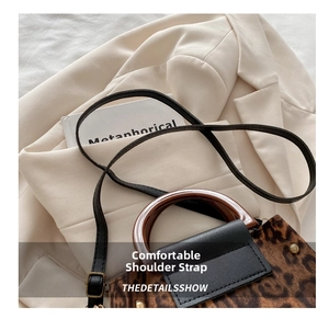 Detail of leopard print handbag featuring translucent acrylic handles and leather strap
