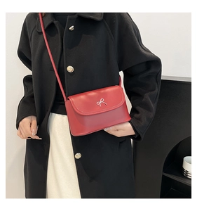 Détail du petit sac carré rouge avec nœud en métal argenté et texture lisse polie