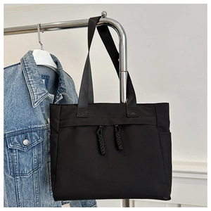 Close-up of black nylon tote bag on hanger with decorative long woven zipper pullers