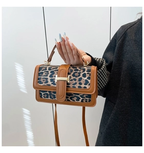 Detailed close-up of leopard print handbag with brown leather trim and golden H-buckle