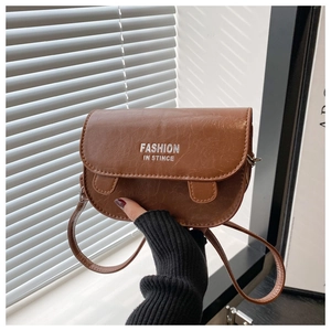 Detail of a brown leather crossbody bag featuring vintage textures and fashion lettering