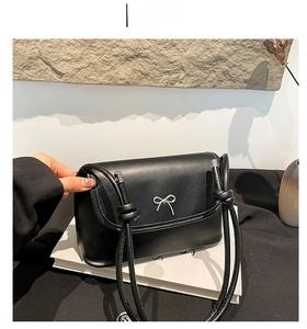 Detail shot of the black leather underarm bag featuring a silver bow metal buckle