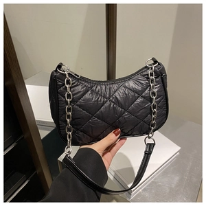 Detail of black quilted shoulder bag featuring silver chain strap and puffer texture