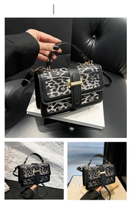 Detail view of leopard print crossbody bag with black leather trim and gold metal buckle