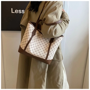 Close-up of diamond pattern canvas tote with brown leather trim details on a model