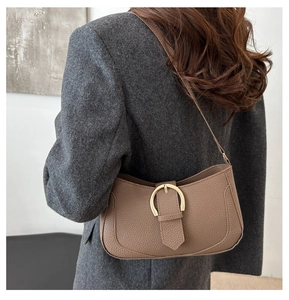 Detail of lychee pattern leather shoulder bag with large gold horseshoe buckle closure