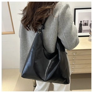 Detail of black leather hobo tote with knotted shoulder strap shown on model back