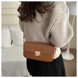 Detail of caramel brown square shoulder bag with gold metal buckle and matte leather