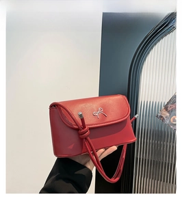 Detail of red leather shoulder bag with silver bow ornament and knotted strap design