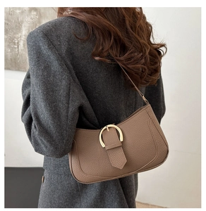 Brown lychee leather hobo bag with a golden horseshoe buckle worn on the shoulder