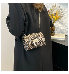 Dettaglio della borsa a tracolla leopardata con catena dorata su un blazer nero