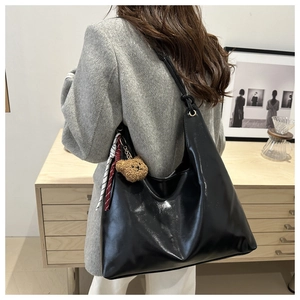 Détail du sac cabas noir brillant avec bandoulière nouée ajustable et breloque ourson