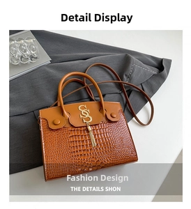 Close-up of brown crocodile texture and golden S-letter tassel detail on handbag