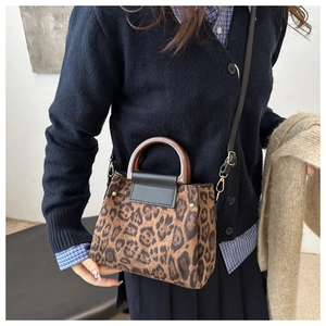 Fashionable leopard print handbag with a circular wooden handle and black leather flap