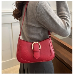Detail view of red lychee grain leather underarm bag with gold horseshoe buckle on model