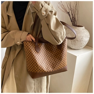 Detailed view of vintage patterned tote bag styled with a classic khaki trench coat