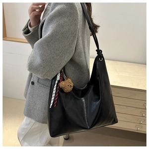 Détail d'un sac cabas en cuir noir avec charm ours et foulard en soie rayé