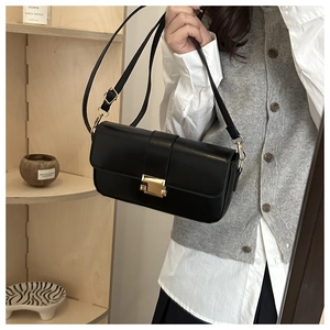 Detail of elegant black crossbody bag with premium gold metal square clasp
