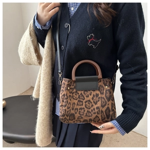 Detail of leopard print handbag with a circular wooden handle and golden rivet accents