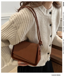Close-up of brown crossbody bag featuring woven texture flap and smooth leather finish