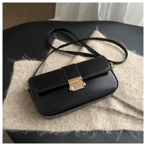 Detail of minimalist black square bag with golden buckle on a beige knit fabric