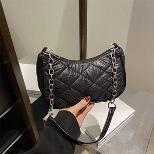 Minimalist black quilted crescent bag with shiny nylon finish and silver chain detail