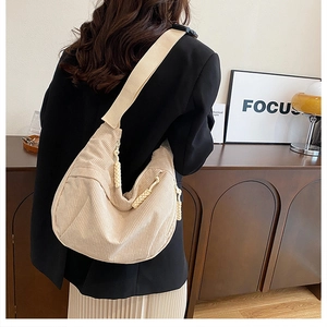 Detailed close-up of beige corduroy hobo bag with knotted rope zipper and focus on texture
