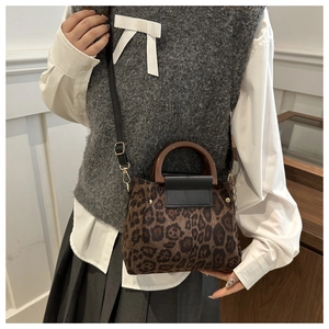 Dettaglio della borsa leopardata con manico in legno scuro e finiture dorate eleganti