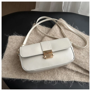 Detail of cream-white vintage shoulder bag with golden metal clasp on knit fabric