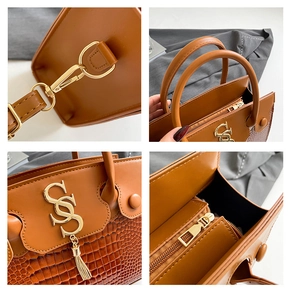 Macro detail of brown crocodile embossed leather, gold hardware and S-letter logo charm