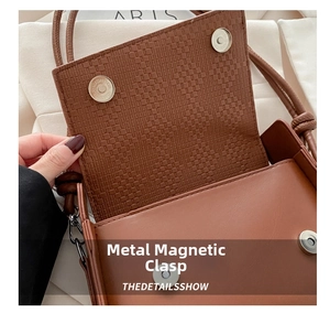 Detail of a brown leather shoulder bag featuring woven texture and double magnetic buckles
