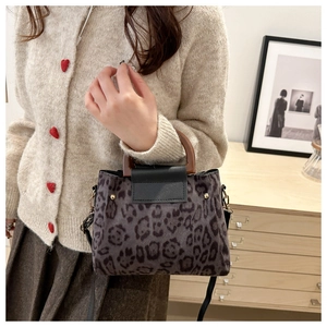 Detail of leopard print handbag featuring a vintage wooden handle and gold rivet accents