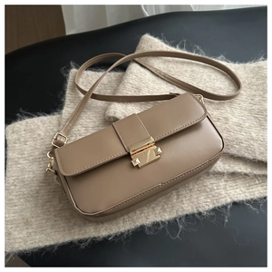 Detail of vintage tan leather crossbody bag featuring a classic gold rectangular buckle