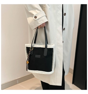 Détail d'un sac cabas en toile noire avec bordure en peau de mouton et écusson